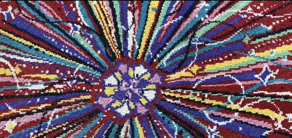 Close-up of The Monte's carpet: a radiating burst of burgundy, indigo, teal, yellow and cream rays